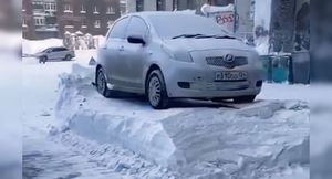 Метровый пьедестал: трактор почистил снег вокруг машин